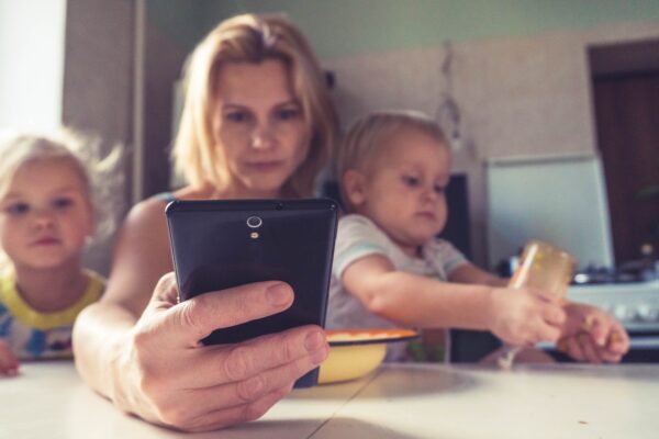 A woman looking at her smartphone next to her two children A woman looking at her smartphone next to her two children (Office of the Ombudsman for Telecommunications).